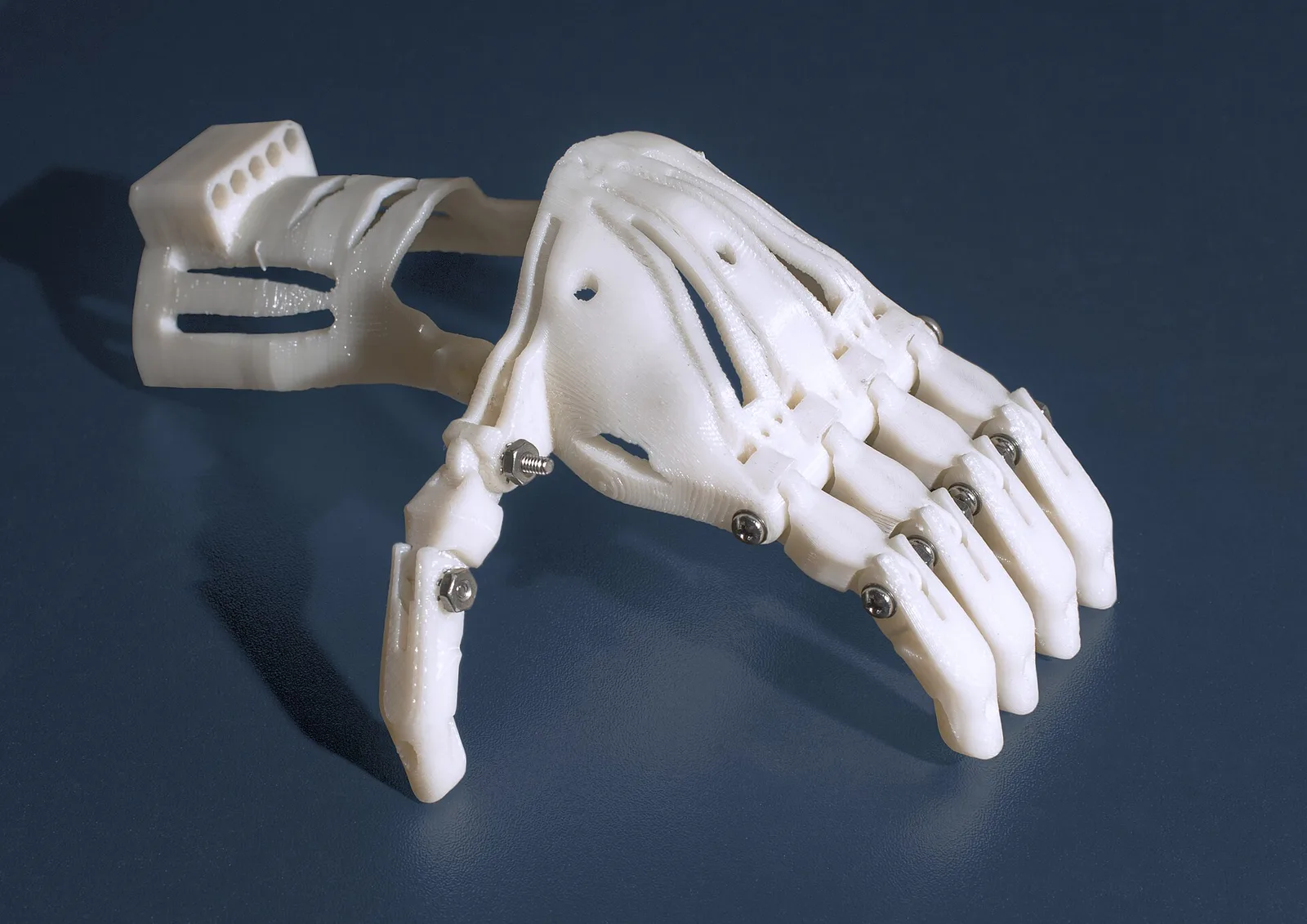 Eine blaue Handprothese aus dem 3D-Drucker, mit Fäden als Sehnen.