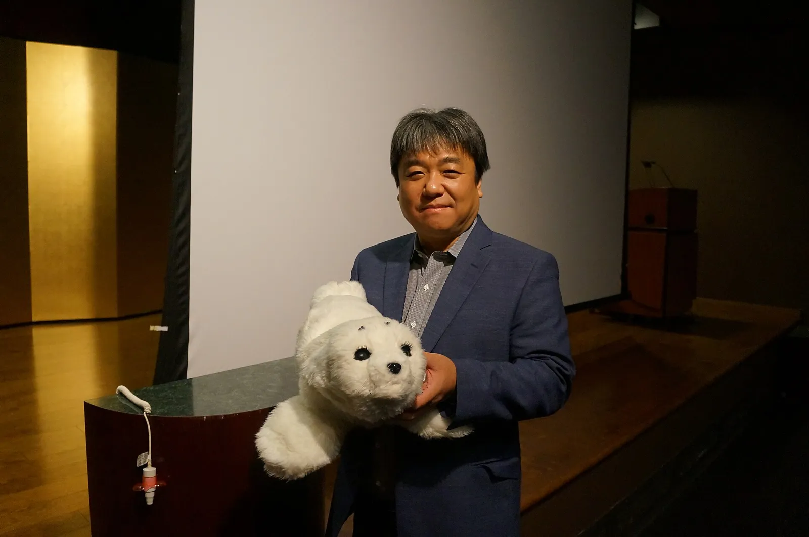 Takanori Shibata hält die weiße Roboter-Robbe PARO im Arm.